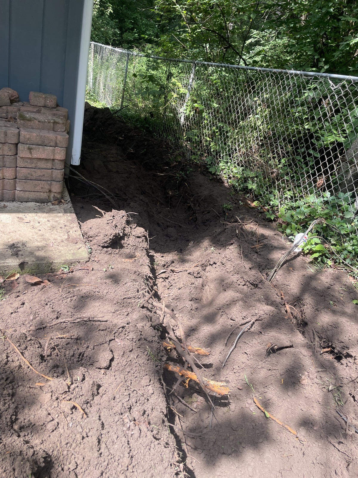 Yard drainage trench along a chain-link fence beside a house in Decatur, IL — Brohez Trucking LLC