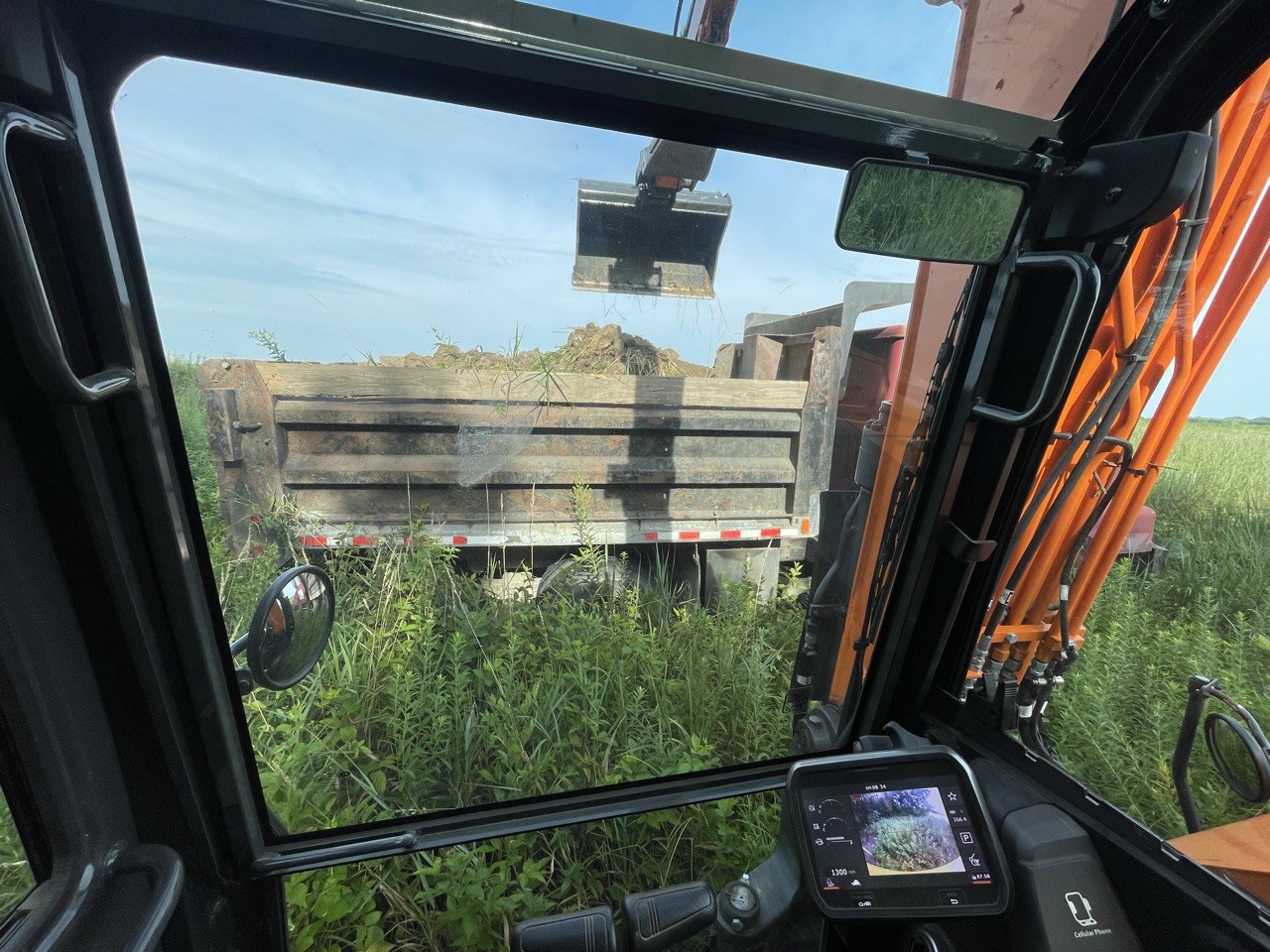 Excavator loading washed-out waterway spoil into a tandem dump truck north of Neoga, Illinois — Brohez Trucking LLC