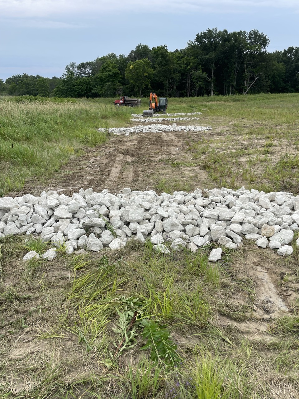Riprap set in the flowline of a repaired grassed waterway near Neoga, IL with the excavator and tandem in the background — Brohez Trucking LLC